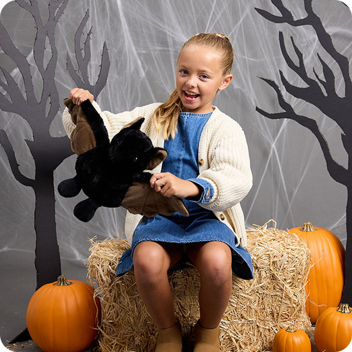 girl holding bat stuffed animal warmies in halloween setting