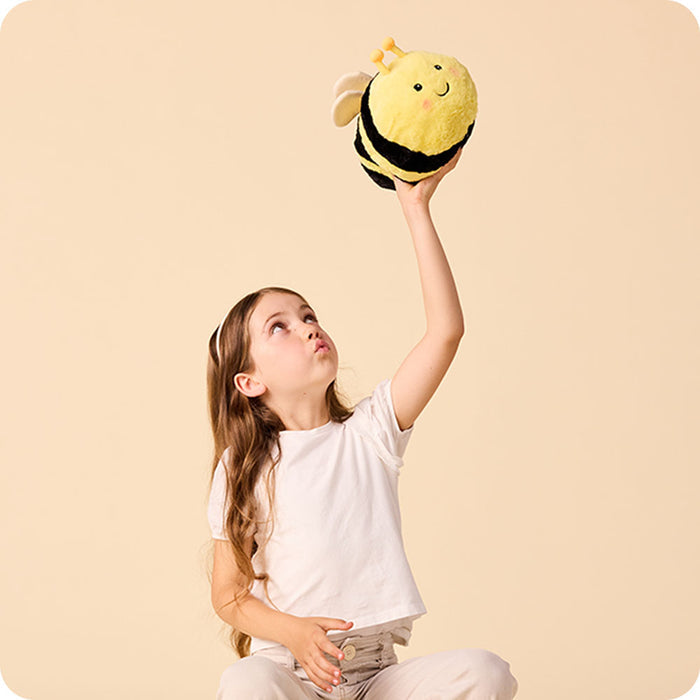 girl holding up a bee stuffed animal warmies