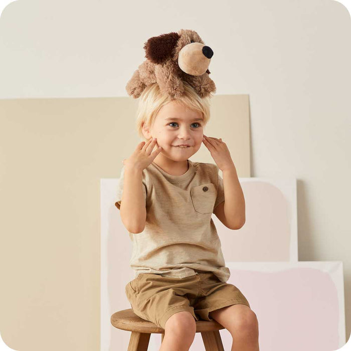 Little boy sitting with Soft Warm Weighted Brown Dog Plush Warmies