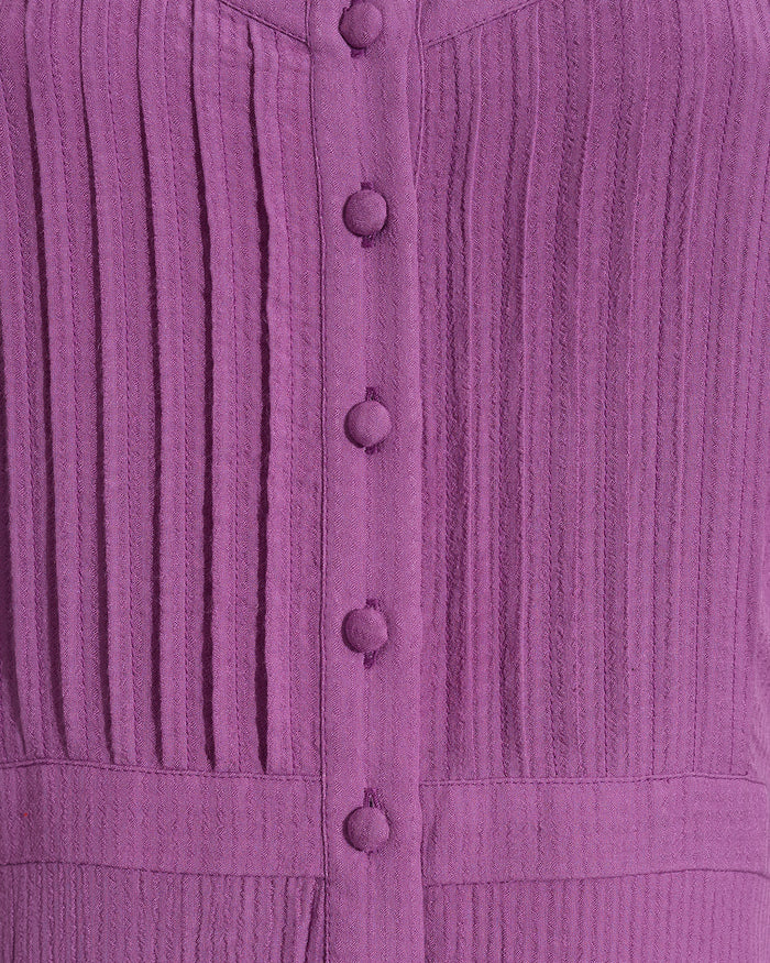Close-up of the Draper James Brynn Sleeveless Midi Dress in Amethyst, a midi dress with vertical pleats and fabric-covered buttons down the front.