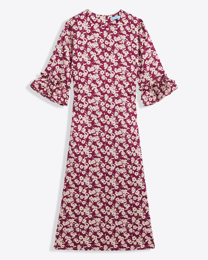The Draper James Crewneck Midi Dress in hammered satin features a maroon and white floral pattern, ruffled cuffs, and a round neckline. Ankle-length with long sleeves. Machine wash cold for easy care.