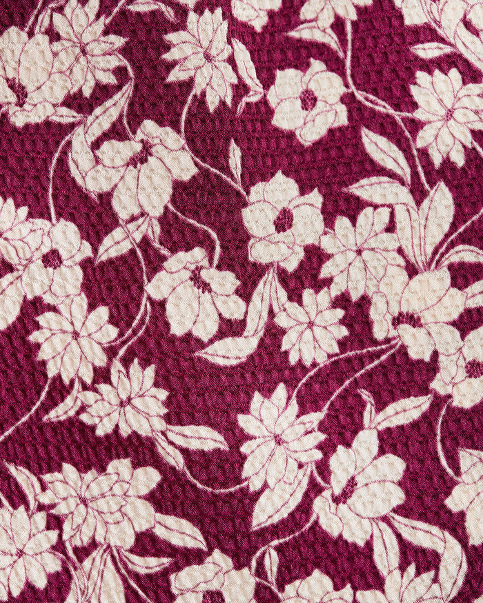 A close-up of the maroon Hammered Satin Crewneck Midi Dress by Draper James shows its textured surface with a cream floral pattern. This elegant polyester dress is easy to care forâ€”just machine wash cold.