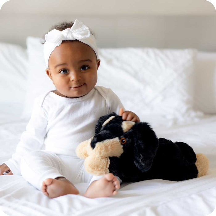 Baby girl holding Soft Warm Weighted Dachshund Plush Warmies
