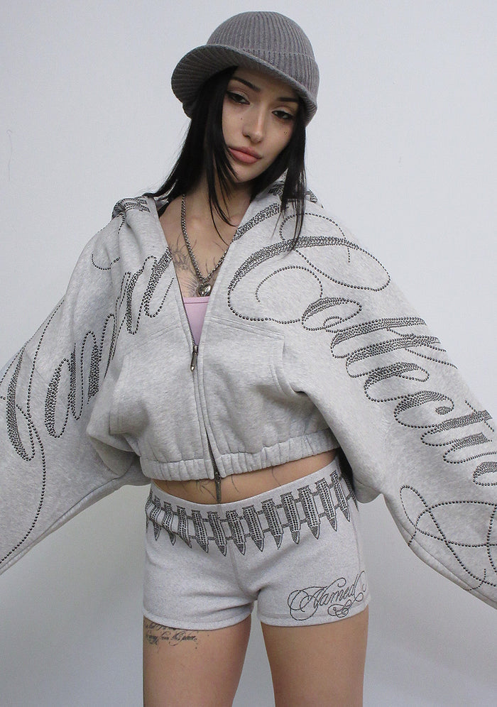 Model wearing the enemy studded crop zip hoodie grey marl with studded logo detail and two-way zip.