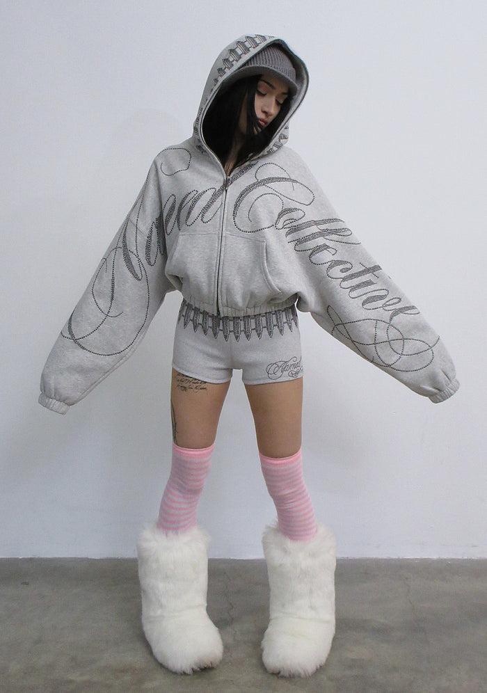 Model wearing grey marl hotpant shorts with studded detailing, paired with a matching oversized grey hoodie.