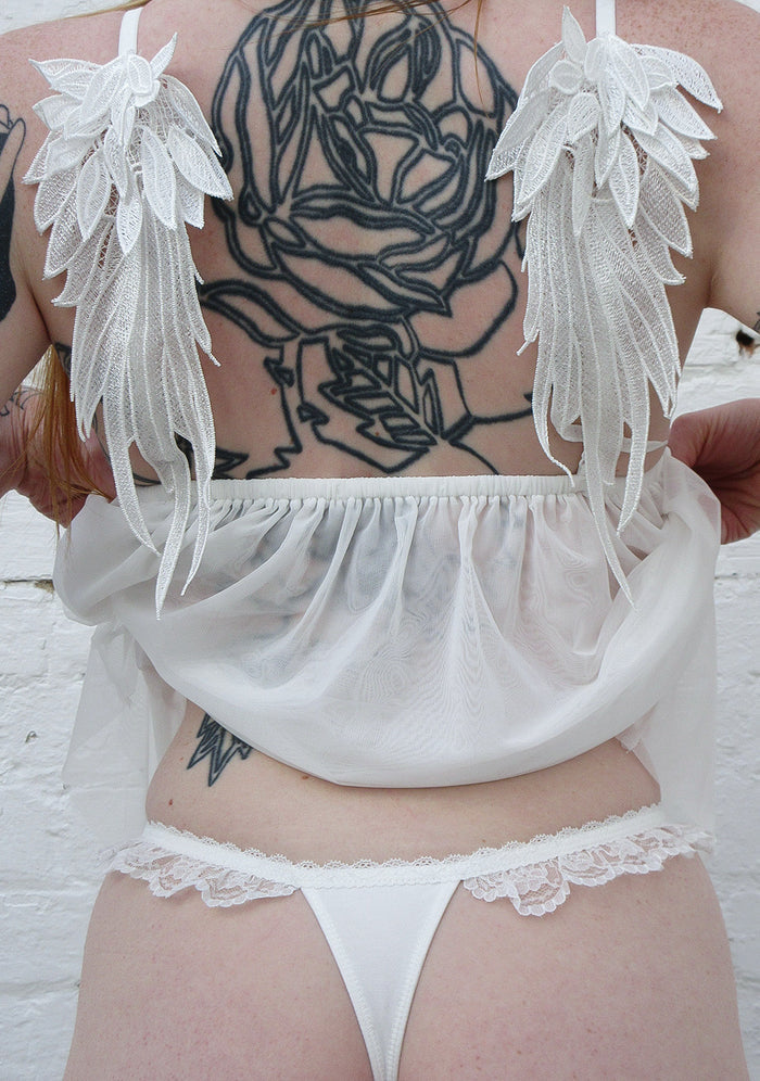 Back view of a white thong with lace trim details, showcasing fallen rhinestone lace ruffle thong white.