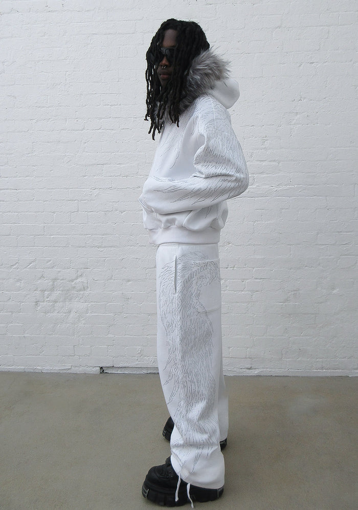 Model wearing white sweatpants featuring a large rhinestone wing design, shown in side view.