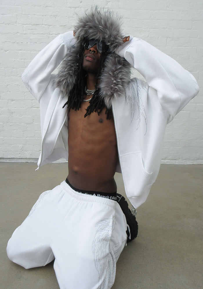 Model wearing white fallen rhinestone oversized sweatpants featuring a detailed rhinestone wing design.