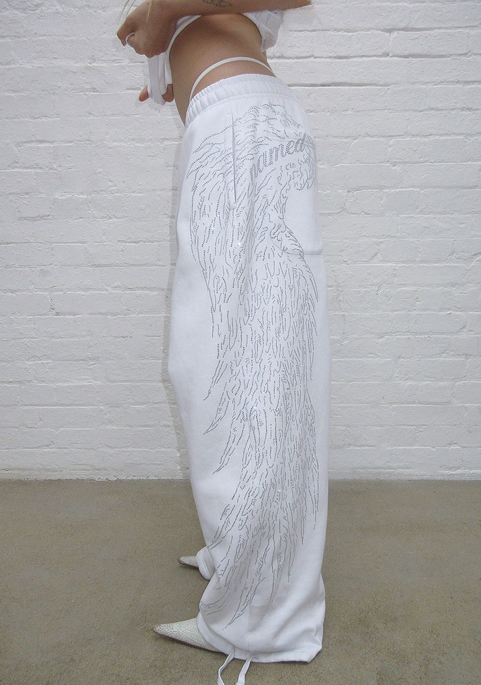 Side view of white sweatpants featuring a large rhinestone wing design.