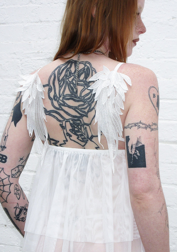 Back view of a model wearing a white cami top with wing details.