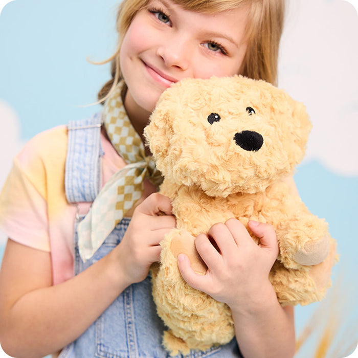 girl holding golden dog warmies stuffed animals