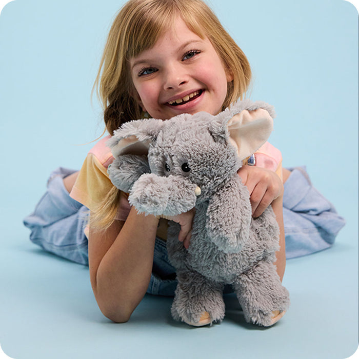 girl holding a warmies elephant stuffed animal