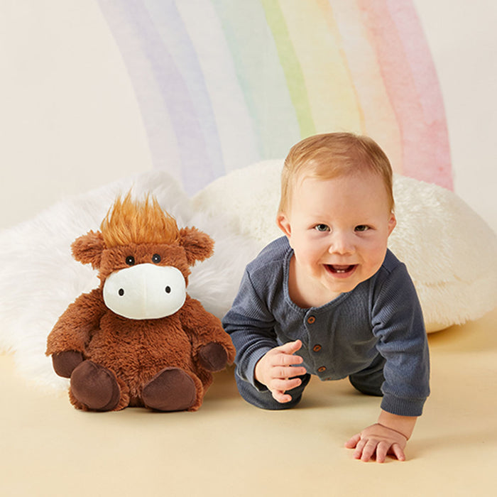 highland cow warmies stuffed animal next to a baby