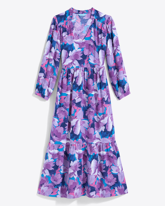 The Draper James Katie Midi Dress boasts a crewneck with a center front keyhole, vibrant floral fabric featuring purple, pink, and white flowers on blue, long sleeves, and a ruffled hem for elegance.