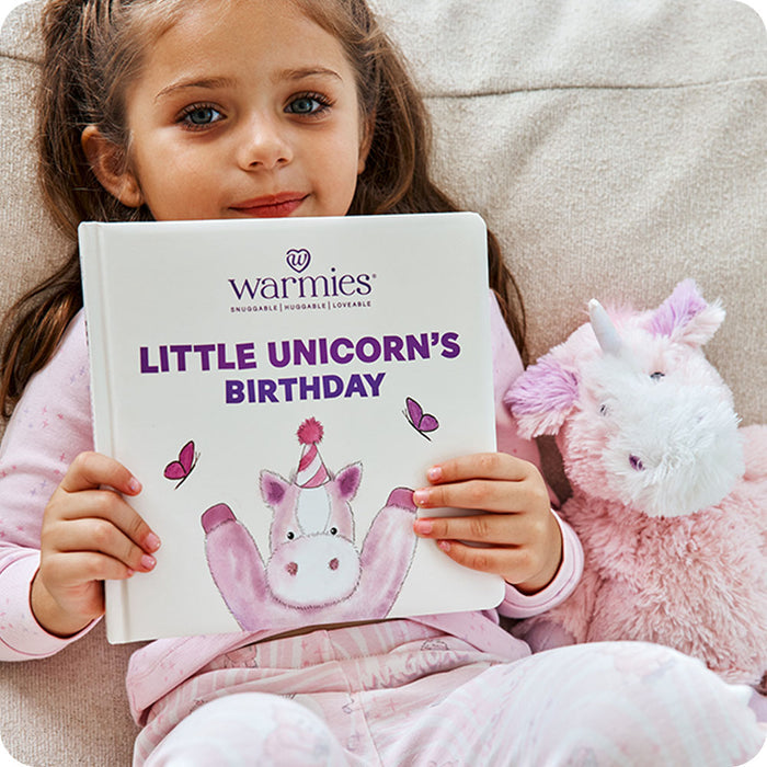 toddler holding Little Unicorn's Birthday book with unicorn stuffed animal