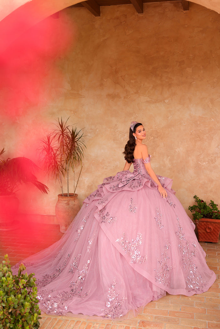 A woman in a lavender ballgown with silver embroidery poses in an archway with terracotta plants.