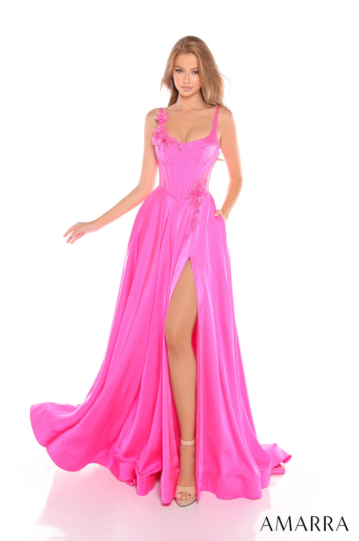 A model wears a long fuchsia evening gown with a thigh-high slit and floral appliqué details.