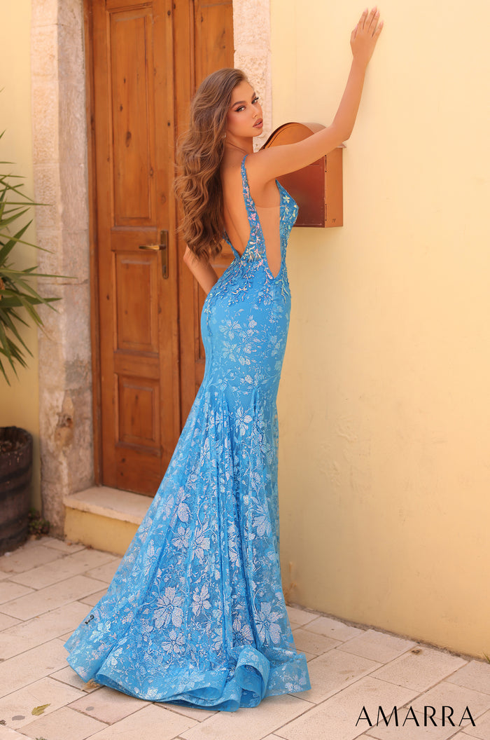 A long blue floral lace mermaid gown with an open back, posed against a wooden door and stone wall.