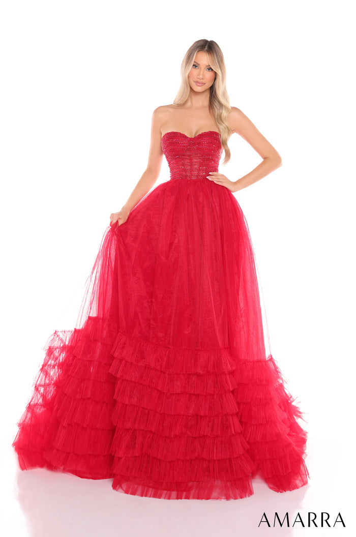 A model wears a strapless, tiered red tulle ball gown with a fitted bodice and full, ruffled skirt.