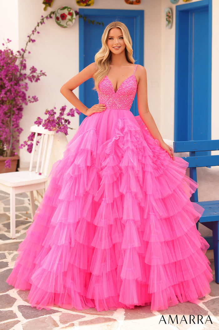 A woman wears a sparkling Hot Pink/Electric Pink tiered ball gown with a beaded bodice against a Mediterranean backdrop.