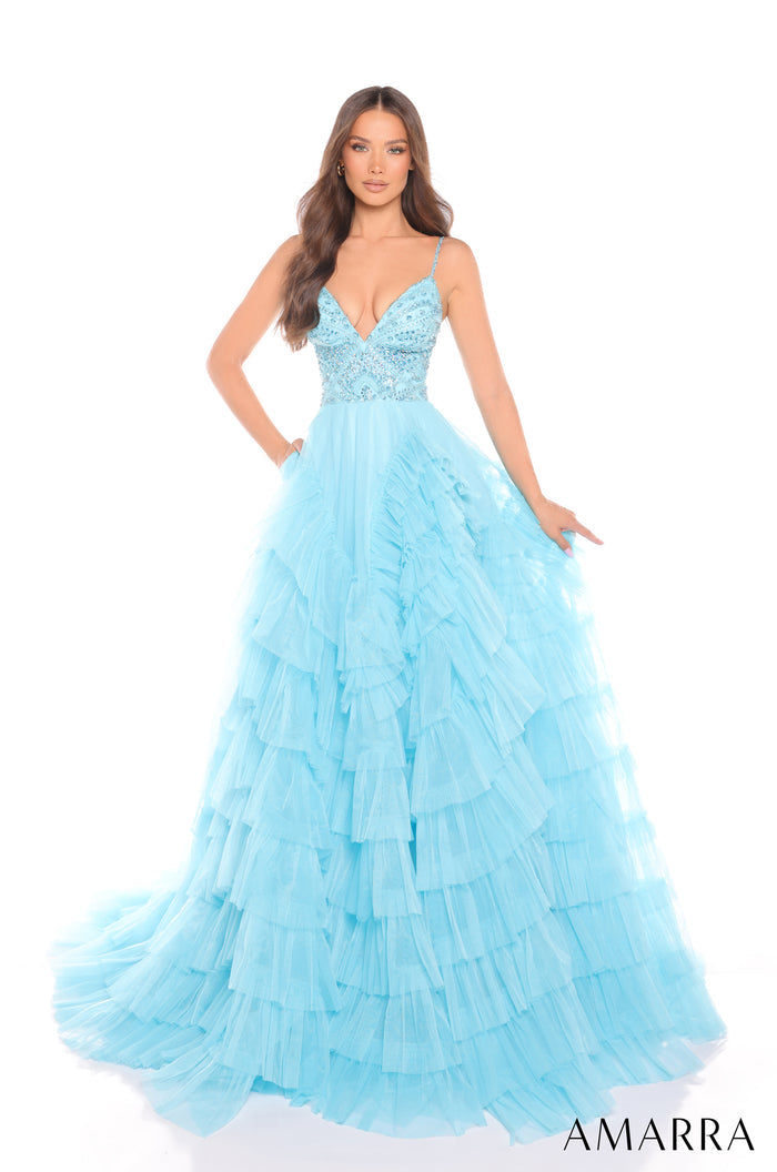 A woman wears a light blue tiered tulle ball gown with a beaded bodice and spaghetti straps.