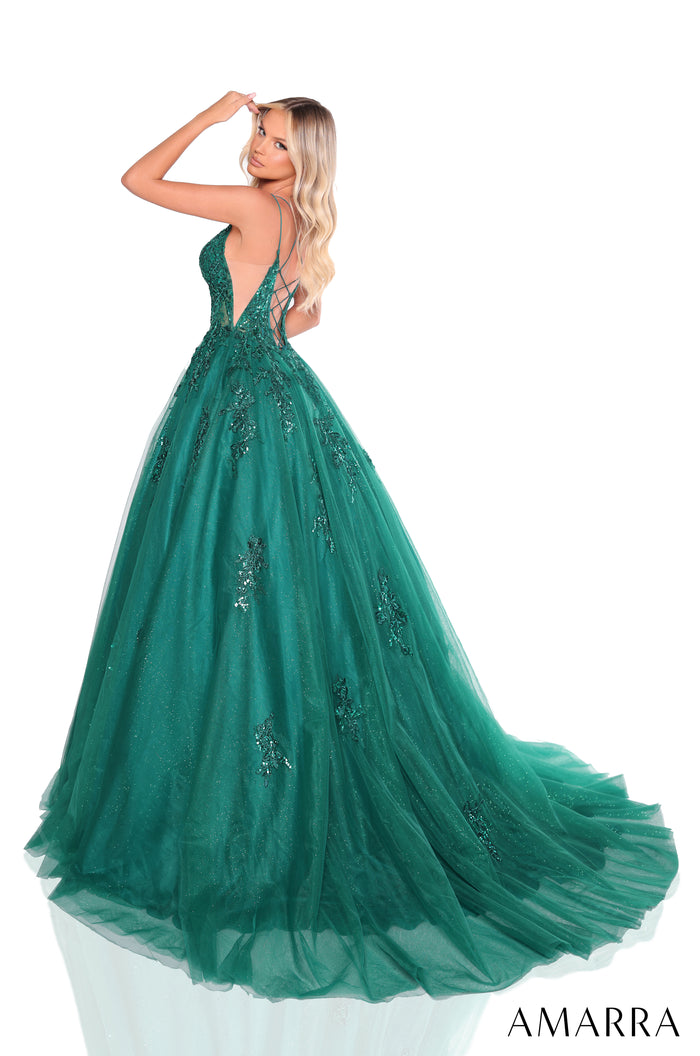 A woman wears an emerald green, floor-length ball gown with sequined appliqués and a plunging back.
