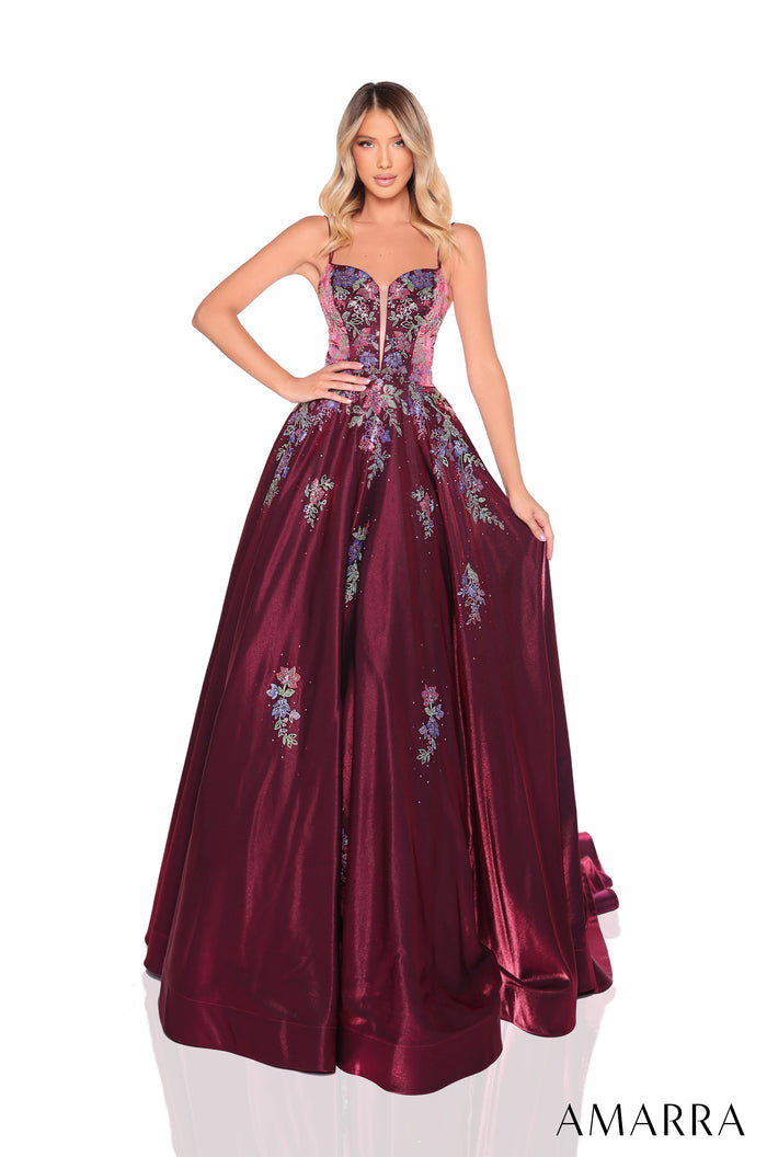 A woman wears a wine-colored ball gown with floral embroidery and a sweetheart neckline.