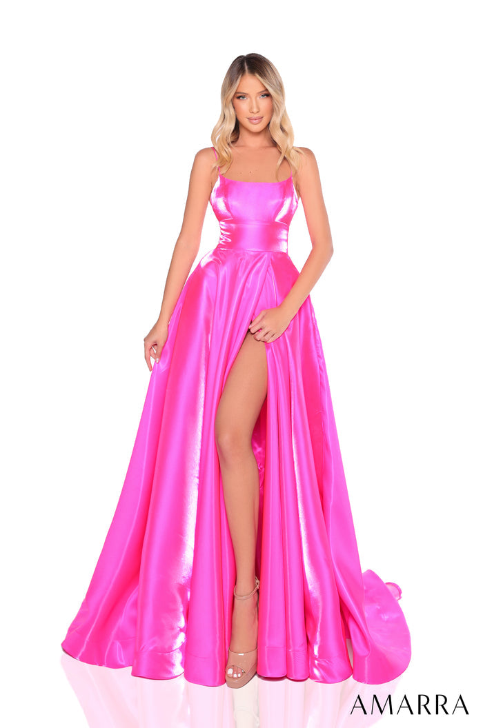 A model wears a shiny, floor-length fuchsia gown with a high slit and thin straps.