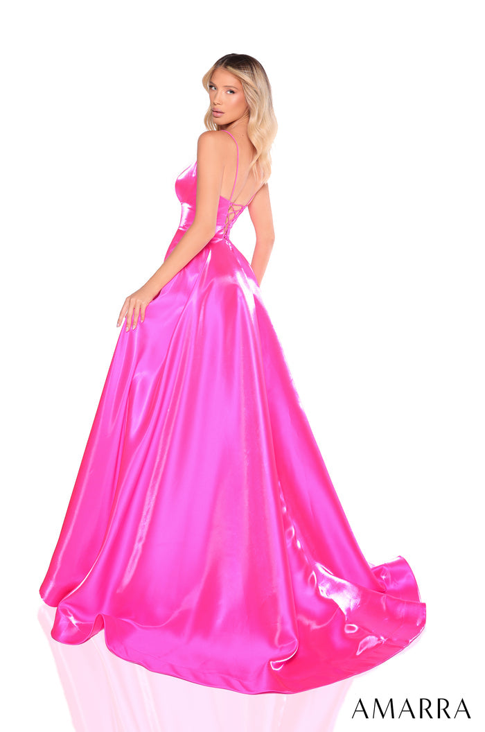A model wears a floor-length, hot pink satin ball gown with a corset-style bodice and a dramatic train.