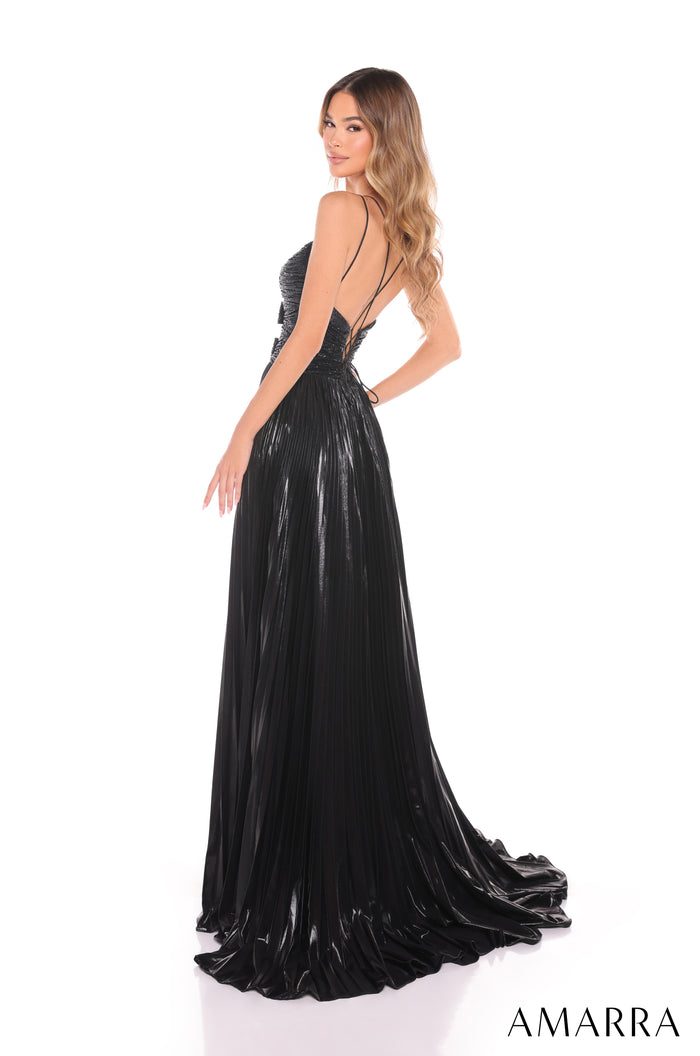A woman wears a black shimmering evening gown with a flowing skirt and thin straps, posing in a side profile.