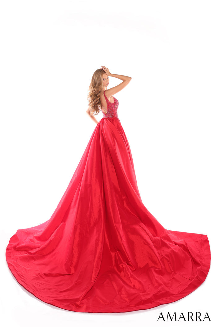 A woman wears a vibrant red ballgown with a beaded bodice and sweeping, voluminous skirt on a white background.