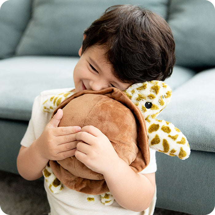 boy hugging sea turtle stuffed animal warmies